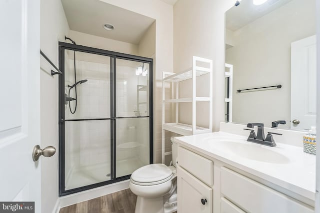bathroom featuring a shower stall, wood finished floors, toilet, and vanity