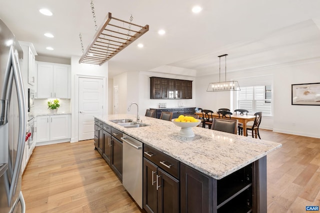 kitchen with a sink, stainless steel appliances, an island with sink, white cabinets, and recessed lighting