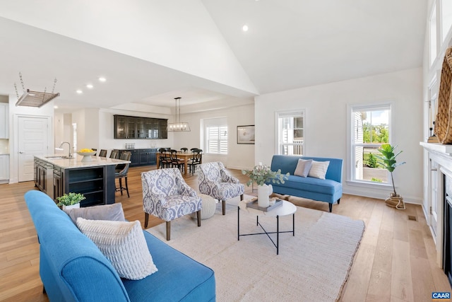 living room featuring a fireplace, light wood-type flooring, recessed lighting, a chandelier, and high vaulted ceiling