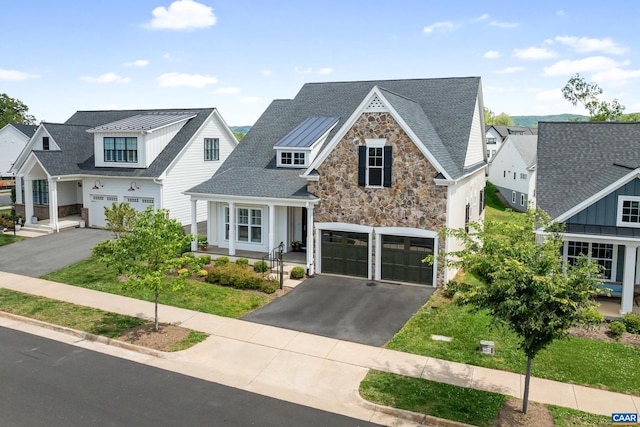 view of front of property featuring asphalt driveway, stone siding, a standing seam roof, and an attached garage