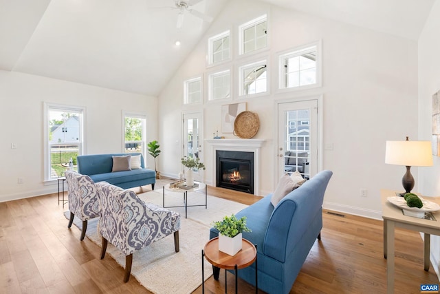 living room featuring high vaulted ceiling, light wood-style flooring, ceiling fan, and baseboards