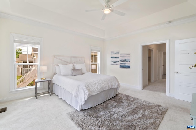 bedroom with light colored carpet, a raised ceiling, a ceiling fan, and baseboards