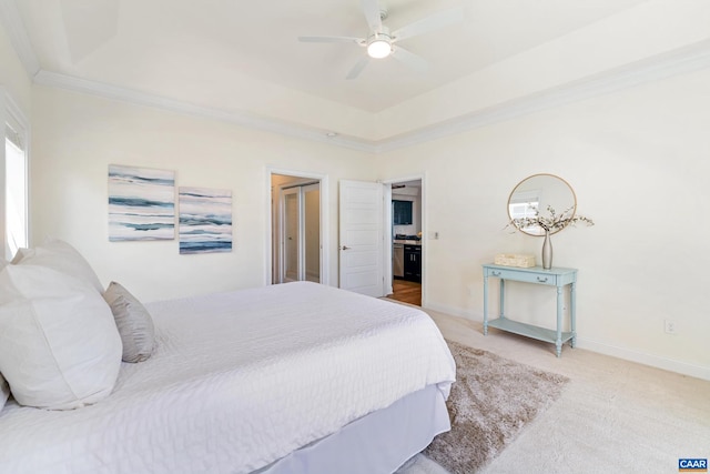 bedroom with carpet, crown molding, baseboards, a tray ceiling, and ceiling fan