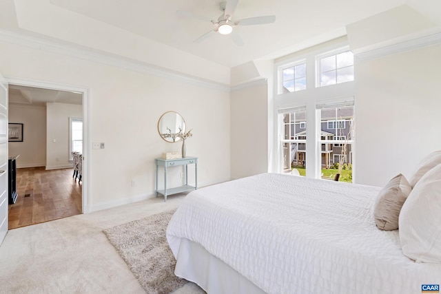 bedroom featuring light colored carpet, multiple windows, baseboards, and a ceiling fan