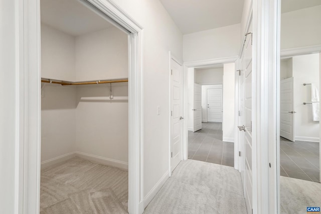 hallway with baseboards, carpet floors, and tile patterned flooring