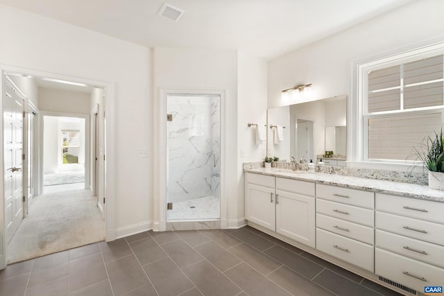 full bath featuring a marble finish shower, vanity, tile patterned flooring, and baseboards