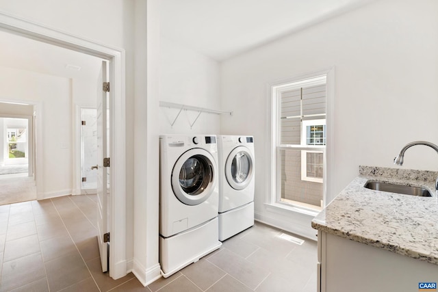 clothes washing area with washing machine and clothes dryer, light tile patterned flooring, and baseboards