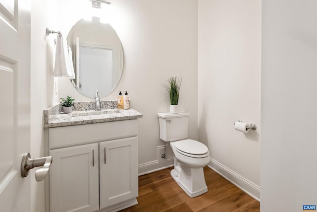 bathroom with baseboards, toilet, wood finished floors, and vanity