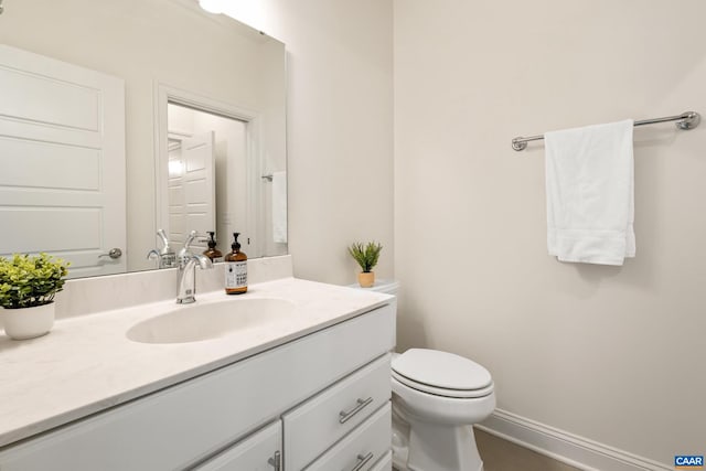 bathroom with vanity, toilet, and baseboards