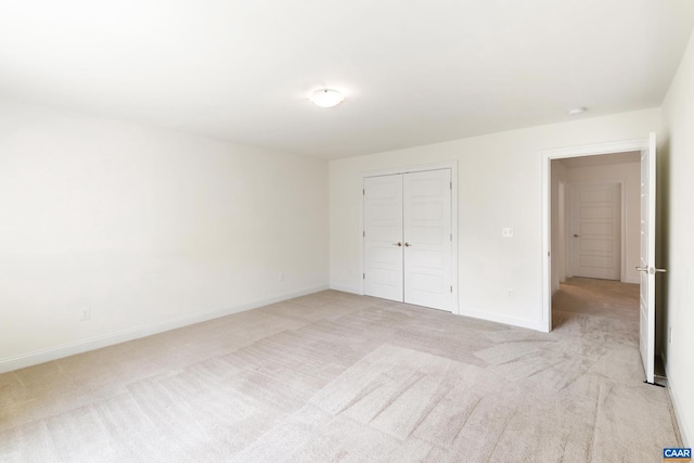 unfurnished bedroom featuring light colored carpet, baseboards, and a closet