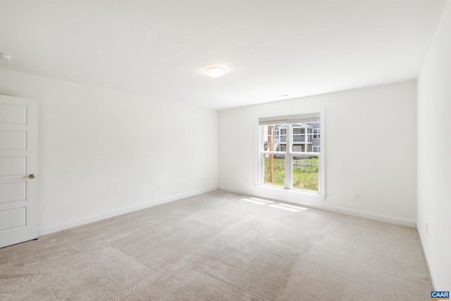 carpeted empty room featuring baseboards and a smoke detector