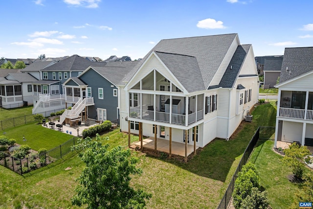 rear view of house with a sunroom, a patio area, a shingled roof, and a residential view