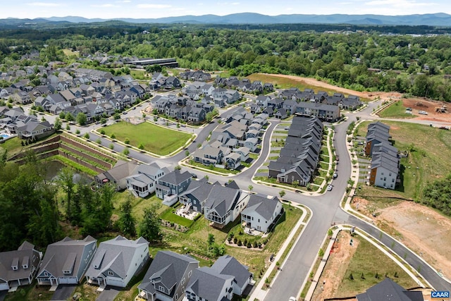 view of property location featuring nearby suburban area, a mountain backdrop, and a forest