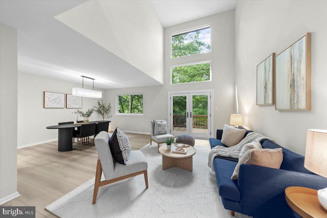 living area with a towering ceiling, wood finished floors, french doors, and baseboards