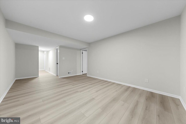 finished below grade area with baseboards and light wood finished floors