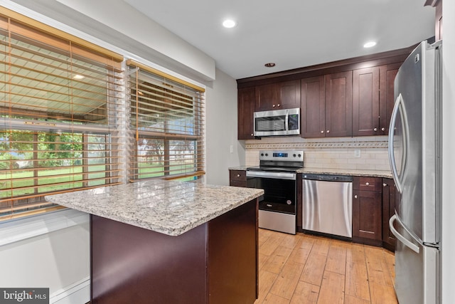 9 Queens Bridge Rd, Levittown, PA 19057 - kitchen with appliances with stainless steel finishes, decorative backsplash, dark brown cabinets, light wood-style flooring, and light stone countertops