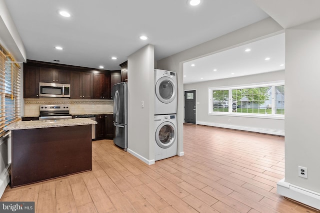 9 Queens Bridge Rd, Levittown, PA 19057 - kitchen with appliances with stainless steel finishes, stacked washing machine and dryer, tasteful backsplash, dark brown cabinetry, and light stone countertops