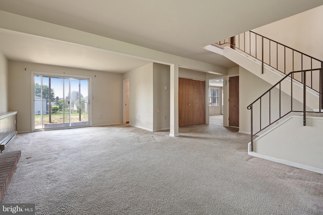 unfurnished living room featuring carpet floors, stairs, and baseboards