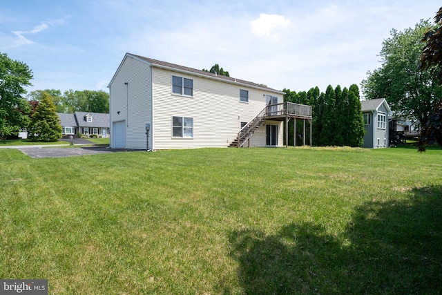 rear view of house with stairway, a wooden deck, driveway, and a yard