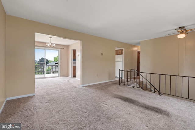 spare room featuring carpet, a chandelier, baseboards, and a ceiling fan