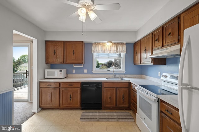 kitchen with white appliances, under cabinet range hood, a sink, light countertops, and brown cabinets