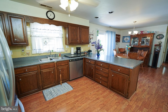 117 Mimosa Dr, Cambridge, MD 21613 - kitchen featuring appliances with stainless steel finishes, a sink, a peninsula, a chandelier, and light wood-style flooring
