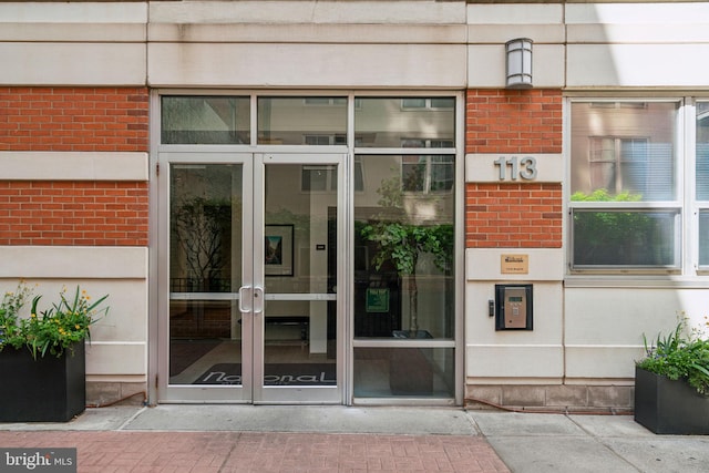 view of exterior entry featuring brick siding and french doors