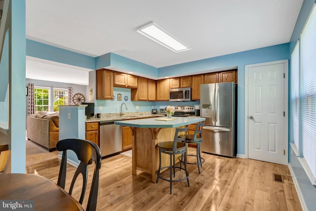 9568 Buttonbush Ct, Manassas, VA 20110 - kitchen featuring appliances with stainless steel finishes, light countertops, a breakfast bar, and light wood-style flooring