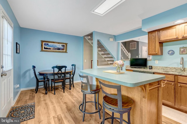 9568 Buttonbush Ct, Manassas, VA 20110 - kitchen with light countertops, a kitchen bar, a kitchen island, light wood-style floors, and a sink