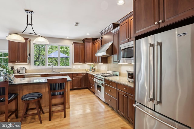 1311 Meadowbrook Ct, Jenkintown, PA 19046 - kitchen featuring high end appliances, a sink, wall chimney exhaust hood, light wood finished floors, and a kitchen bar