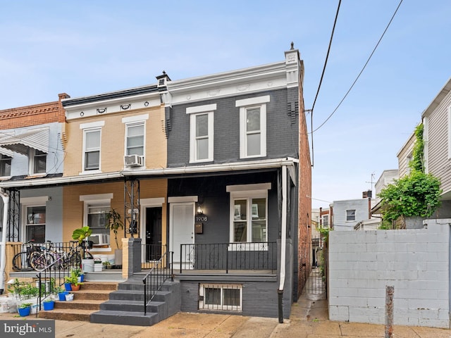 multi unit property featuring covered porch, brick siding, fence, and cooling unit