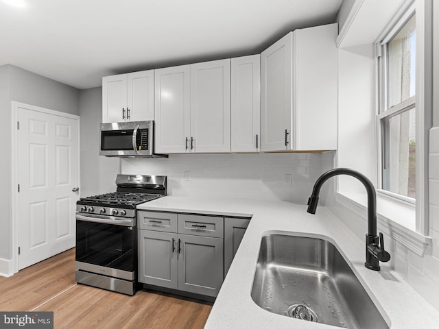 kitchen featuring stainless steel appliances, a sink, light countertops, and backsplash