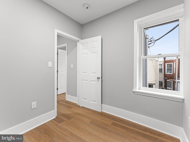 empty room featuring wood finished floors, baseboards, and a smoke detector