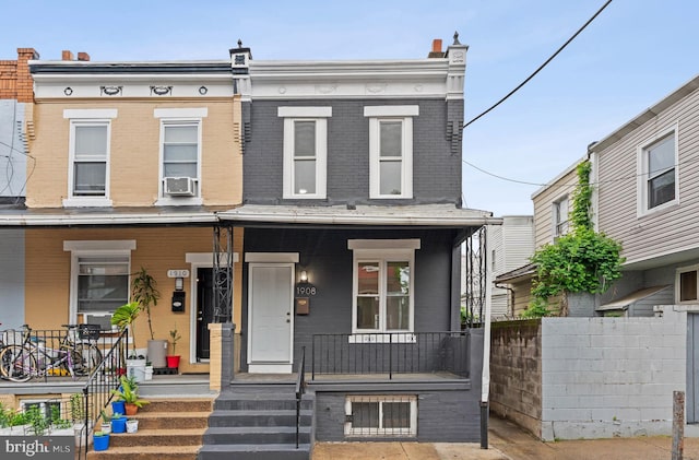 multi unit property featuring a porch, brick siding, and fence