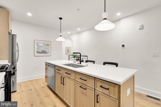 kitchen with a sink, light brown cabinetry, dishwasher, light wood finished floors, and recessed lighting