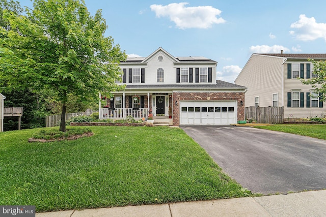view of front facade featuring brick siding, covered porch, asphalt driveway, solar panels, and an attached garage
