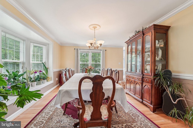 dining room featuring a chandelier, light wood-style flooring, crown molding, and baseboards