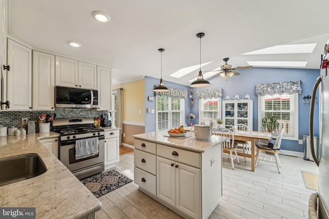 kitchen featuring stainless steel appliances, a skylight, backsplash, light wood-style flooring, and recessed lighting
