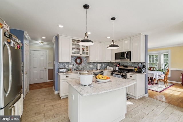 kitchen with stainless steel appliances, crown molding, light wood-style flooring, white cabinets, and baseboards