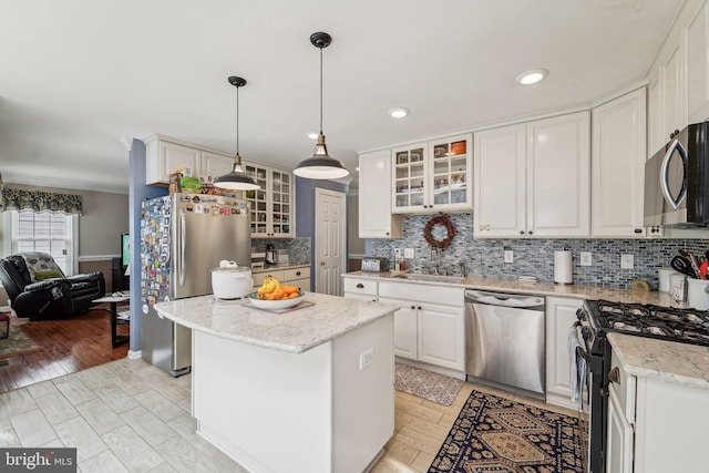 kitchen with stainless steel appliances, a kitchen island, tasteful backsplash, glass insert cabinets, and white cabinets