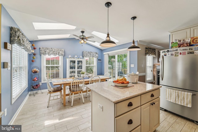 kitchen with freestanding refrigerator, a skylight, light wood-type flooring, a kitchen island, and lofted ceiling