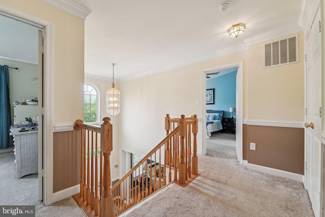 corridor with an upstairs landing, carpet flooring, ornamental molding, a chandelier, and baseboards