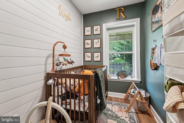 bedroom with wood walls, wood finished floors, and baseboards