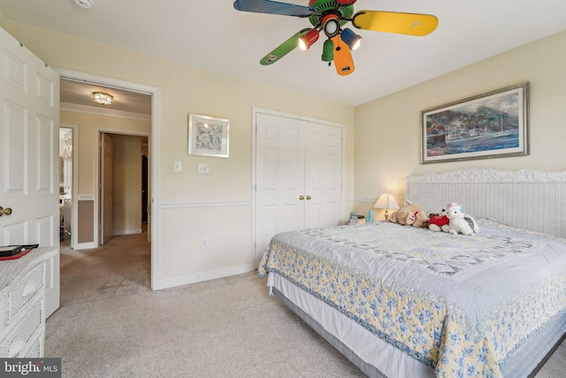 carpeted bedroom with a closet, baseboards, a ceiling fan, and ornamental molding
