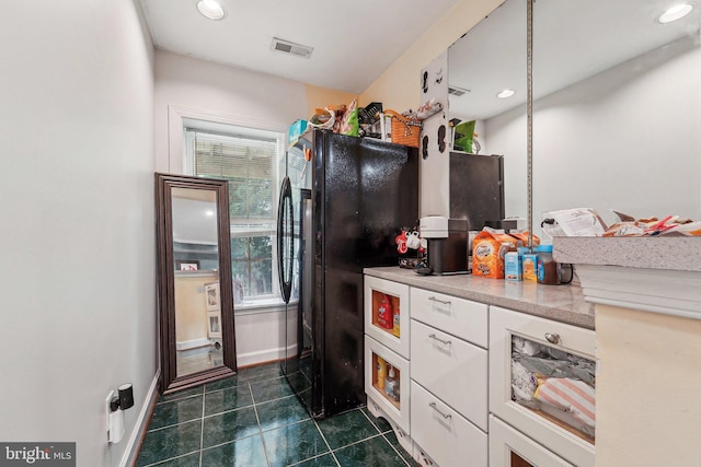 kitchen featuring plenty of natural light, white cabinets, freestanding refrigerator, dark tile patterned floors, and recessed lighting