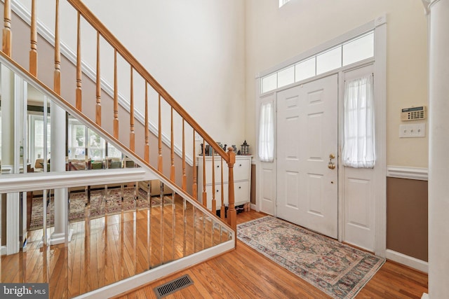 entrance foyer featuring plenty of natural light, wood finished floors, baseboards, a high ceiling, and stairs