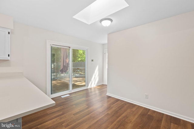 unfurnished dining area featuring a skylight, dark wood-type flooring, and baseboards
