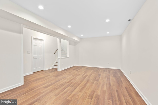 finished basement with light wood-style flooring, stairway, recessed lighting, and baseboards