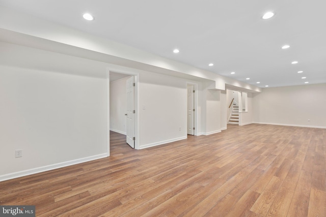 finished below grade area featuring recessed lighting, light wood-style flooring, stairway, and baseboards