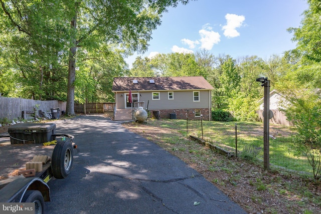 view of front of house featuring fence, asphalt driveway, and brick siding